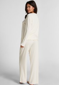 Crème ribbed lounge-outfit set met een lange mouw top met een ronde halslijn en bijpassende wijde broek met gegolfde zoom.