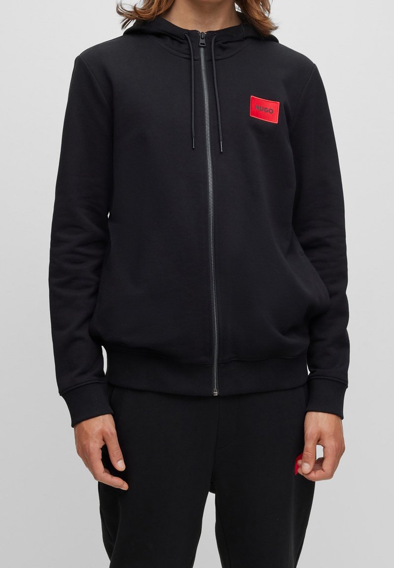 Černá mikina na zip vyrobená z bavlněné směsi, s předním logem v červené barvě, nastavitelnou kapucí se šňůrkou a žebrovanými manžetami a lemem.