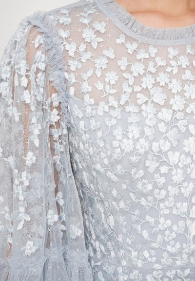 Jasnoniebieska sukienka z przezroczystą kwiatową haftowaną tkaniną, falbaniastym dekoltem i bufiastymi rękawami z tiulu o misternych zdobieniach.