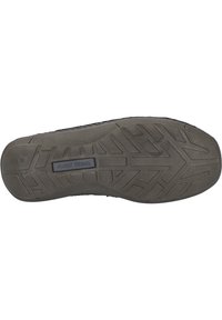 Shoe sole featuring a textured rubber surface in dark gray with a geometric tread pattern and a central brand logo.