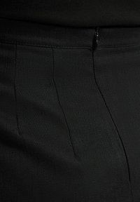 Zwarte broek met een gladde textuur, gestructureerd ontwerp en subtiele streepjes, met een verborgen ritssluiting bij de taille voor sluiting.