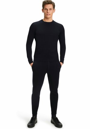 Marineblaue gerippte Strickpullover mit langen Ärmeln, kombiniert mit passenden Slim-Fit-Jogginghosen, ergänzt durch schwarze lässige Sneakers. Minimalistisches Design, weicher Stoff.