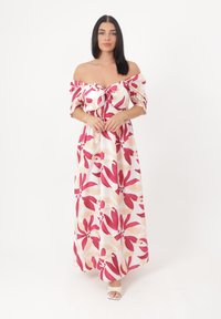 Robe maxi avec un design à épaules dénudées, présentant des motifs floraux roses et beiges sur un fond blanc, et un corsage froncé.