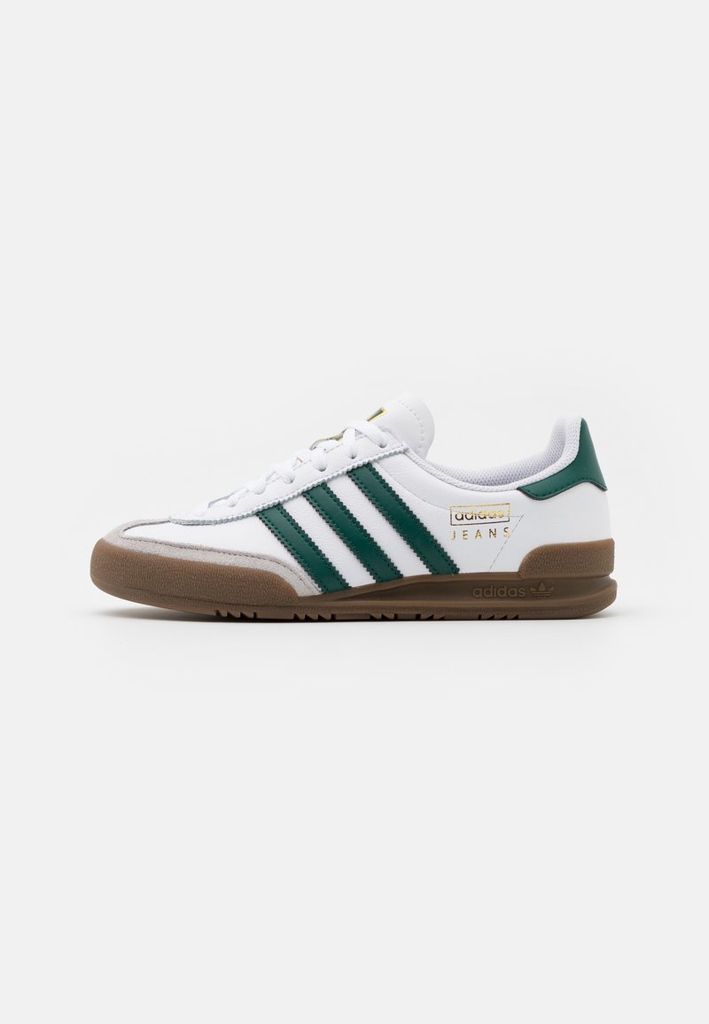 White sneakers with green stripes, suede accents, and a gum rubber sole. Features a classic design with branding on the side.