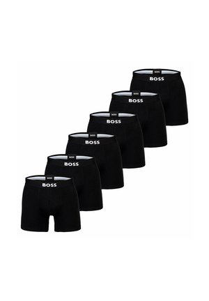 Schwarze Boxershorts in einer Reihe ausgestellt, mit einem weißen Logo auf dem elastischen Bund. Glatter Stoff, eng anliegendes Design.