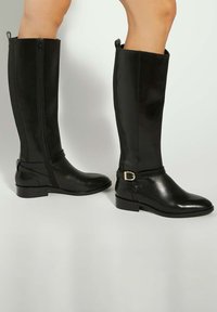 Black knee-high boots made of smooth leather, featuring a side zipper, a buckled strap detail, and a flat heel for stability.