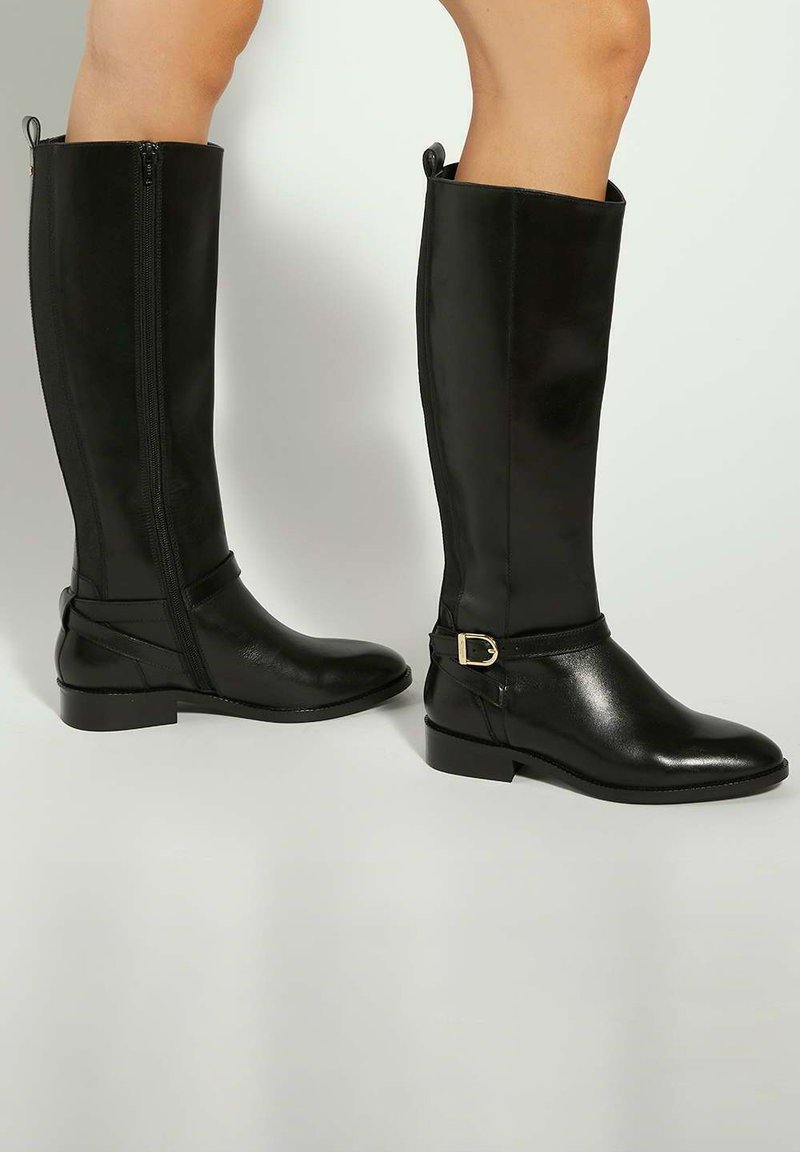 Black knee-high boots made of smooth leather, featuring a side zipper, a buckled strap detail, and a flat heel for stability.