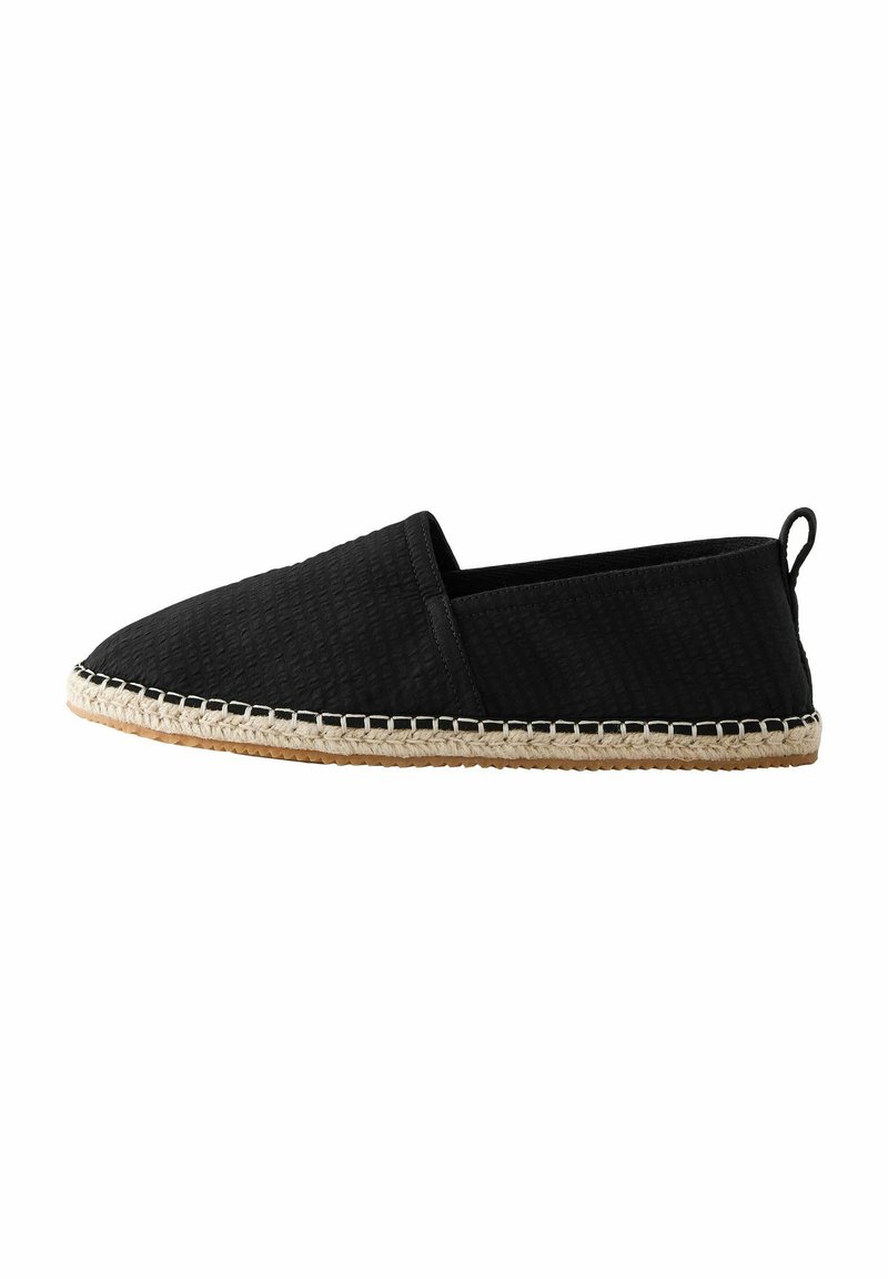 Espadrille noire à enfiler avec tige en tissu texturé, semelle en jute et couture contrastante le long du bord. Design minimaliste.