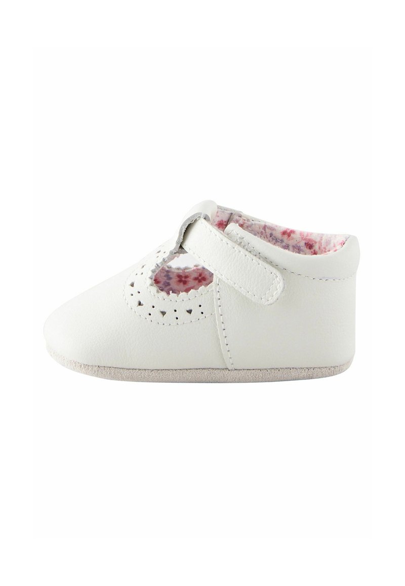 Chaussure en cuir blanc avec une forme arrondie, des découpes décoratives sur le dessus et une doublure douce avec un motif floral. Fermée par une sangle en Velcro.