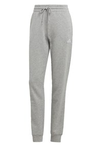 Pantalons de survêtement en coton gris avec une coupe fuselée, une taille élastique avec cordon de serrage, et un petit logo blanc sur la cuisse gauche.