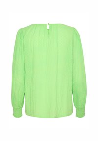 Blouse verte texturée à manches longues, dotée d'une ouverture en forme de clé au dos, de poignets élastiques et d'un motif à pois sur l'ensemble.