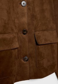 Hnedá semišová bunda z predu s tromi tmavými gombíkmi a dvoma veľkými klopovými vreckami.