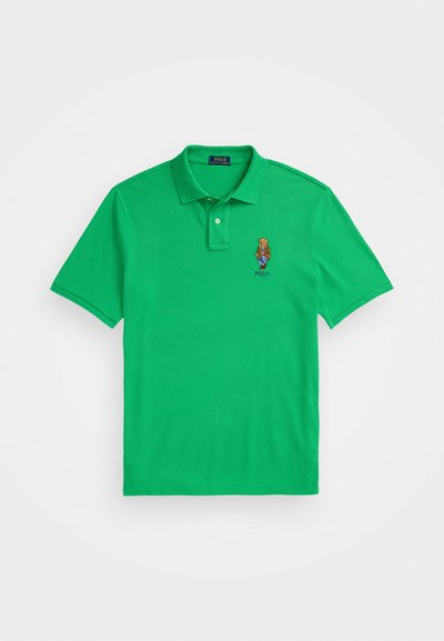Roheline polo särk, mis on valmistatud puuvillast, selles on kaelus, lühikesed varrukad ja vasakul rinnal brodeeritud logo. Sujuv tekstuur.