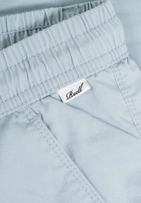 Tela de color azul claro con una superficie texturizada, que presenta una cinturilla elástica y una pequeña etiqueta de la marca cosida en el material.
