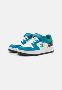 Blaue und weiße Sportschuhe mit einem Klettverschluss, schwarzer Sohle und grünen Akzenten; verfügen über eine perforierte Textur im Zehenbereich und an der Seite.