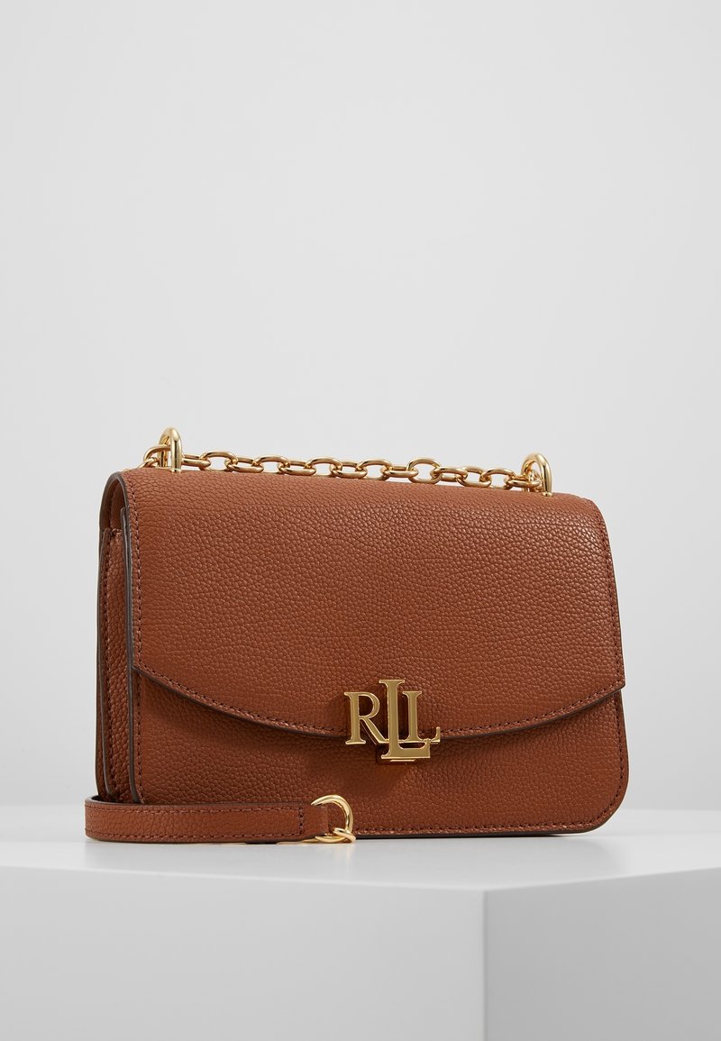 Brązowa torebka skórzana o fakturze, z złotym łańcuszkiem, z zapięciem na klamrę i wytłoczonym złotym logo z przodu.