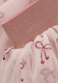 Tissu en tulle rose avec de jolis nœuds brodés brillants et une taille en métal rose texturé. Présente des fronces douces et une apparence transparente.