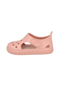 Sandalia de goma rosa con detalles recortados, una correa de gancho y bucle, suela texturizada y un logo en la correa. Diseñada para ofrecer comodidad y ventilación.