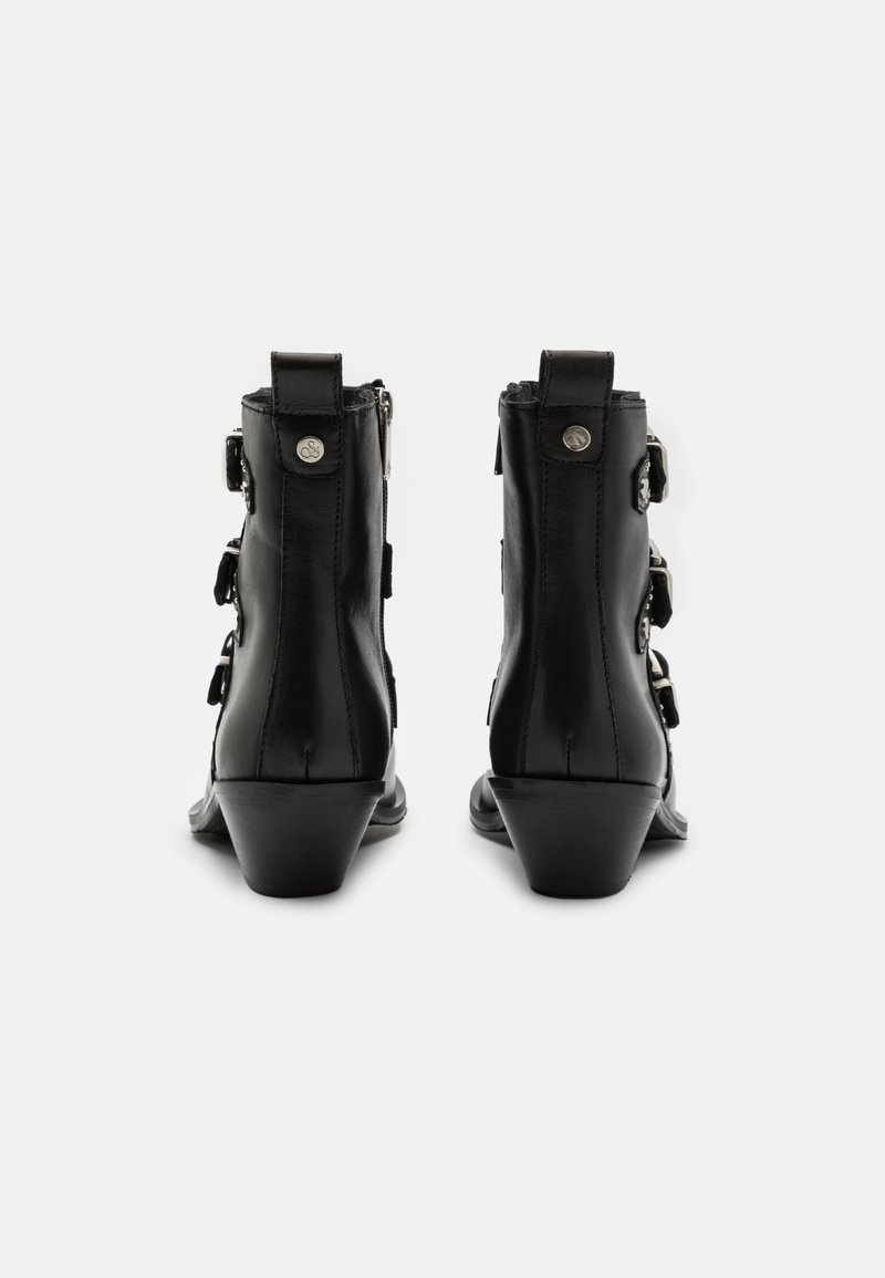 Stivaletti in pelle nera con un leggero tacco, caratterizzati da tre fibbie decorative e una cerniera sul lato per facilitare l'indossamento.