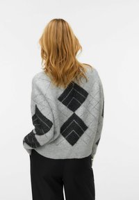 Szary sweter z czarnym wzorem argyle, o teksturowanym wykończeniu i prążkowanym dole. Widok z tyłu ukazuje luźny, oversize'owy fason.