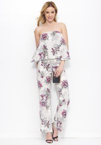Jumpsuit w kwiatowy wzór z bezrękawową, rozszerzaną górą w odcieniu szarym, z różowymi i zielonymi akcentami. Gładki materiał o szerokich nogawkach, zestawiony z kopertówką.