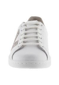 Vit sneaker sedd framifrån, med vita snören och en glittrande silversidodetalj, samt en strukturerad vit sula.