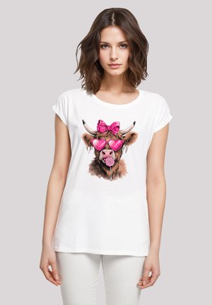 Weißes Baumwoll-T-Shirt mit einem bunten Grafikmotiv einer Kuh mit pinken Sonnenbrillen, einer Schleife und einem Lutscher, vor einem neutralen Hintergrund.