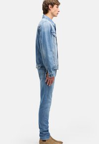 Spijkerjack en spijkerbroek in lichtblauw, slim fit. Het jack heeft twee borstzakken, een knoopsluiting en contrasterende stiksels. Suède Chelsea-laarzen.