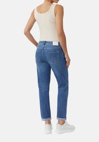 Hellblaue Denim-Jeans mit geradem Bein und umgeschlagenen Säumen, ausgestattet mit zwei Gesäßtaschen und einem weißen Etikett am Bund.