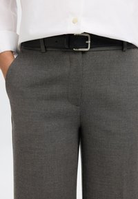 Sivé nohavice z textúrovanej látky s rovným predným dielom, bočnými vreckami a čiernym koženým opaskom so striebornou prackou.