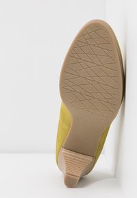 Chaussure en daim vert avec une semelle en caoutchouc, dotée d'un talon texturé et strié et d'une forme de bout lisse et arrondie. Taille marquée comme 37.