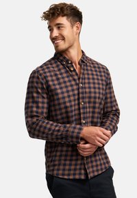 Brun og marineblå ternet button-up skjorte i blødt stof, med lange ærmer og klassisk krave. Træknapper accentuerer fronten.