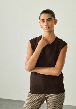 Top en maille sans manches marron avec un col rond et un ourlet côtelé, associé à un pantalon à motif à carreaux en beige, marron et rose.