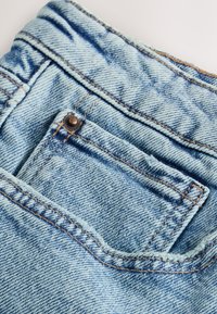 Světle modré džínové kalhoty s zadní kapsou s jednoduchým designem, viditelným šitím a mírně opraným okrajem.