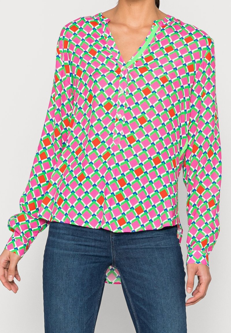 Blusa a maniche lunghe in un vivace motivo geometrico rosa, verde e arancione. Caratterizzata da un colletto a V, apertura con bottoni e vestibilità comoda.