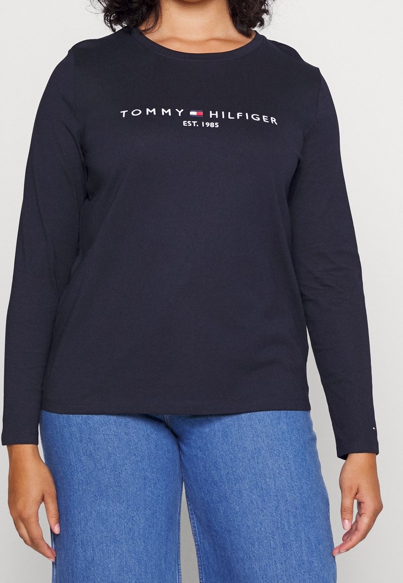T-shirt a maniche lunghe nera con scollo rotondo, caratterizzata dal logo bianco "TOMMY HILFIGER EST. 1985" sul petto, realizzata in morbido cotone.