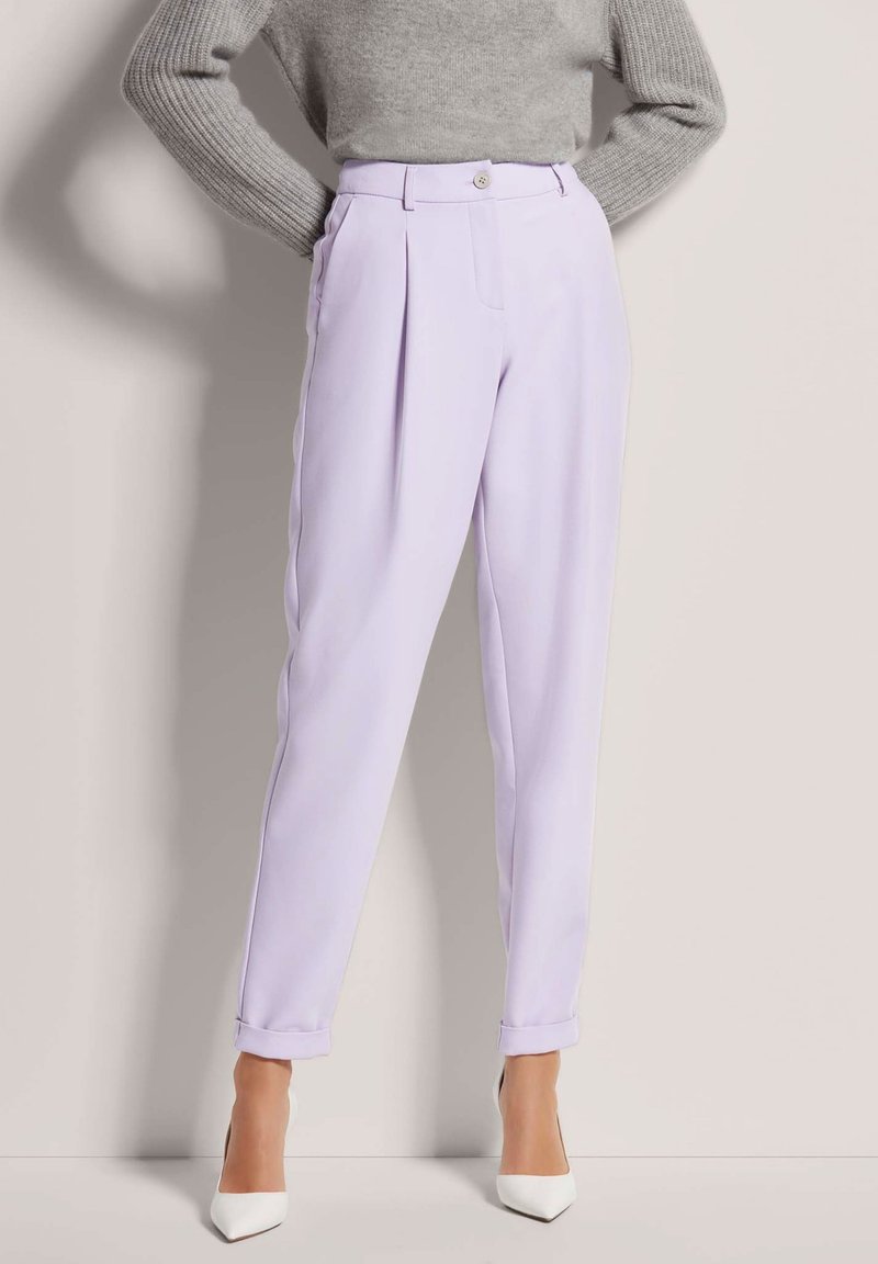 Lilac tailored trousers with front pleats, featuring a single button closure, cuffed hems, paired with white pointed-toe heels.