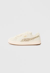 Grietos nubukinės sportbačiai su smėlio spalvos raštuota šonine juostele, apvaliu nosiu, raištelių užsegimu ir tekstūruotu guminio pado dizainu.