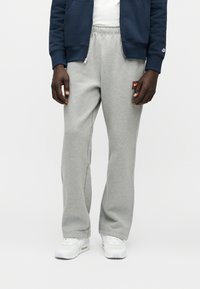 Γκρι παντελόνι φόρμας από βαμβακερό μείγμα ύφασμα, με ελαφρώς φαρδιά γραμμή, ελαστική μέση και μικρό κόκκινο λογότυπο Nike στο πλάι.