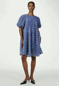 Modré kvetinové šaty s textúrovanými aplikáciami ruží, krátkymi puff rukávmi a nariaseným pásom, doplňujúce voľný A-liniový tvar.