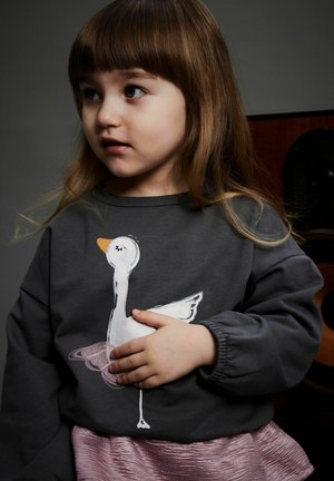 Gray sweatshirt featuring a white goose illustration, paired with a iridescent pink skirt. Texture is smooth, with elastic cuffs.
