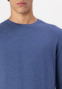 Blue knit sweater featuring a crew neckline, ribbed cuffs, and a soft texture. The fabric appears lightweight and slightly heathered.
