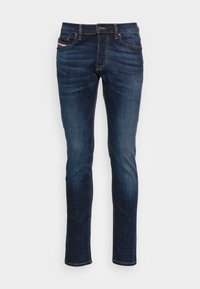 Slim-fit mörkblå denim jeans med standard femficksdesign, mässingsknäppning och kontrasterande gula sömmar. Slät textur.