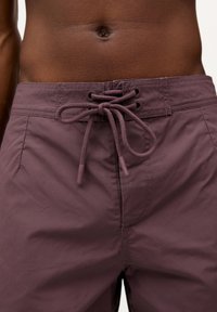 Shorts de înot maron închis cu un finisaj texturat, talie elastică și sistem de închidere cu șnur. Prezintă ochiuri întărite pentru o durabilitate sporită.