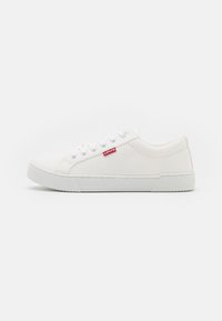 Witte canvas sneakers met een laag design, ronde neus, platte zool en een rood logo op de zijkant. Voorzien van witte veters en stikaccenten.