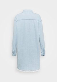 Robe chemise en denim bleu clair avec col, manches longues et poignets boutonnés. Présente un ourlet effiloché et un détail au yoke arrière.