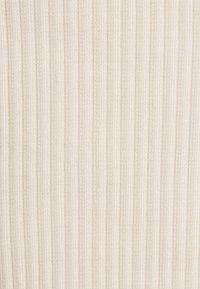 Krämfärgad ribbad tyg med inbäddade vertikala linjer, som visar en mjuk struktur och enhetlig färg genom hela materialet.