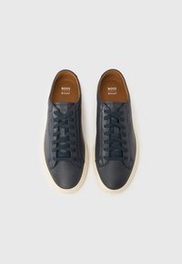 Baskets en cuir marine avec bouts ronds, semelles intérieures marron et lacets assortis. Dotées d'une semelle en caoutchouc blanche contrastante et d'un logo embossé.