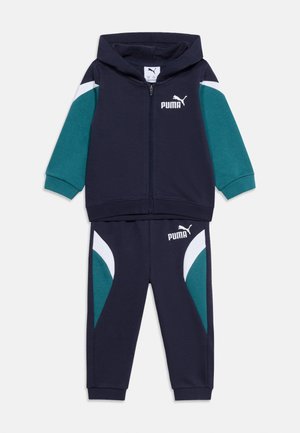 Navy blue and teal children’s Puma tracksuit with white logo, zip-up hooded jacket, and matching pants with color-block panels.