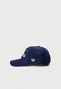 Navy blue cap made of textured fabric, featuring white embroidered lettering and a small logo on the side. Curved brim and six-panel design.